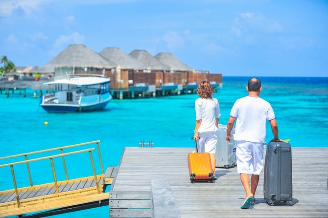 People with suitcases by the beach
